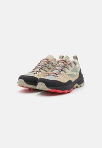 Tan and black outdoor shoes with red accents, featuring a textured upper, lace closure, and rugged outsole designed for traction.