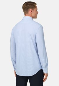 Camicia da uomo azzurro chiaro a maniche lunghe con sottili righe verticali. Presenta un colletto standard e polsini con bottoni, realizzata in tessuto liscio.