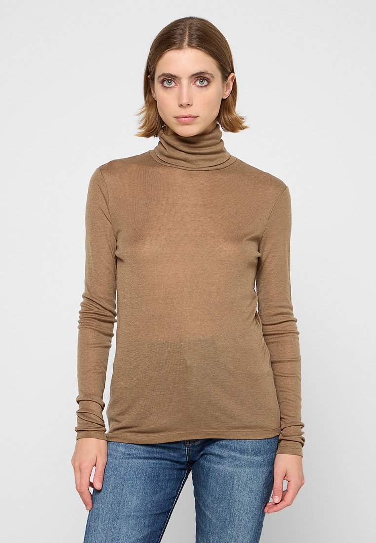 Maglione a collo alto marrone a maniche lunghe in un tessuto trasparente, caratterizzato da una silhouette aderente e una consistenza liscia, abbinato a jeans in denim blu.