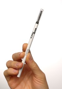 Crayon à sourcils avec un corps cylindrique blanc et un capuchon transparent comportant un peigne. L'étiquette du produit indique "CRAYON À SOURCILS Rodial" en texte noir.