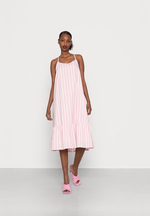 Pink striped dress with a flared ruffle hem, featuring thin straps and a loose fit. Paired with pink block-heeled sandals.