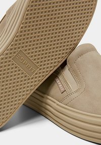 Baskets beige à enfiler avec une semelle en caoutchouc texturée et le logo Esprit sur le côté et la semelle, présentant un design de chaussures décontracté et confortable.
