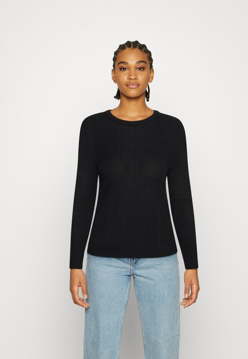 Sweater preto com riscas, de mangas longas e decote redondo, combinado com jeans de um azul claro. Textura suave, design ajustado.