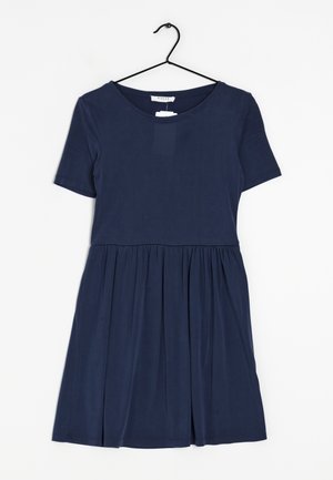 Vestido de manga corta azul marino hecho de un tejido suave, con un top ajustado y una falda acampanada con detalles fruncidos en la cintura. Cuelga en un gancho negro.