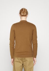 Brauner, gestrickter Pullover mit geripptem Muster, runder Ausschnitt und langen Ärmeln. Verfügt über einen taillierten Saum und Bündchen, ideal zum Lagenlook.