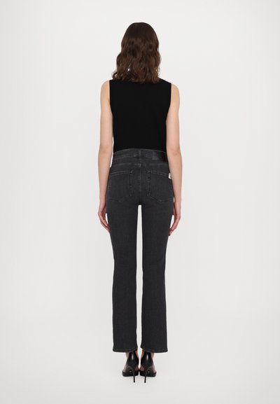 Sort ærmeløs top parret med mørkegrå vidde jeans. Slim fit med baglommer, med let struktur og et rent design.
