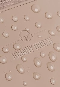 Materiale impermeabile beige con gocce rialzate e logo "JOHNNY URBAN" impresso, con una superficie liscia e una leggera lucentezza.