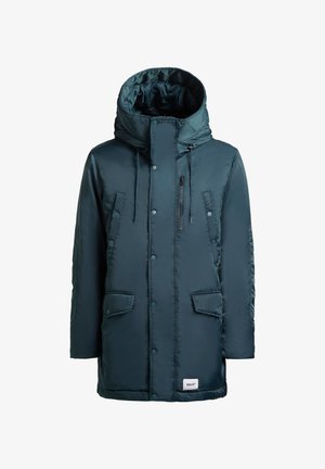 Parka imbottita color teal con un ampio cappuccio, due tasche davanti e una tasca sul petto con zip. Dotata di bottoni a pressione e regolazioni con cordino.
