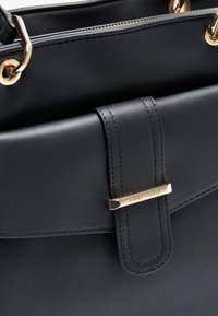 Black leather handbag featuring a smooth texture, a structured design, gold hardware accents, and a front flap with a brand detail.
