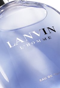 Lanvin L'homme Eau de Toilette i en transparent, kurvad glasflaska med en ljusblå vätska, som har svarta och silverfärgade textetiketter.