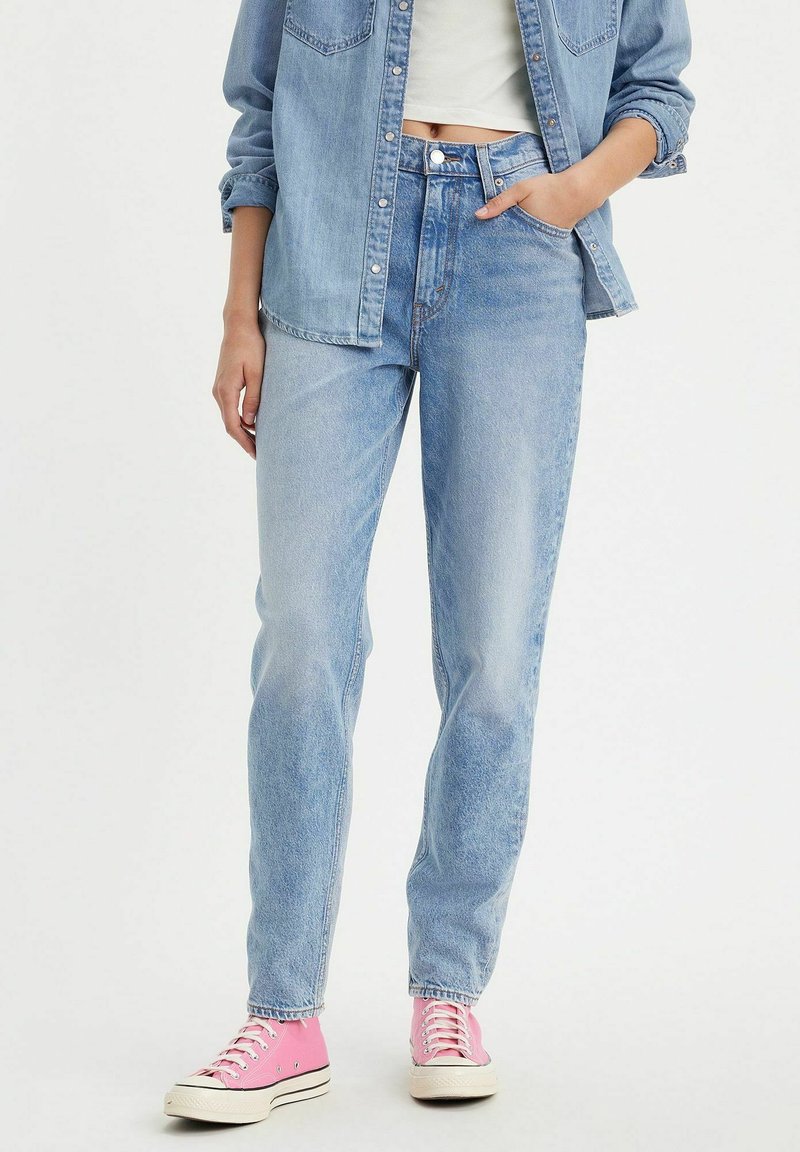 Lichtblauwe denim jeans met een hoge taille en rechte pijpen. Gecombineerd met een lichtblauw overhemd en rozenkleurige sneakers. Eenvoudig ontwerp en stiksels.