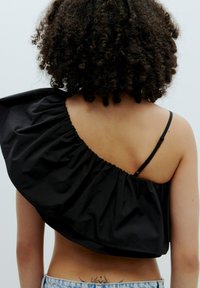 Schwarzes Carmen-Oberteil mit Rüschendesign, aus glattem Stoff gefertigt. Verfügt über einen dünnen, verstellbaren Träger und einen abgerundeten Saum.