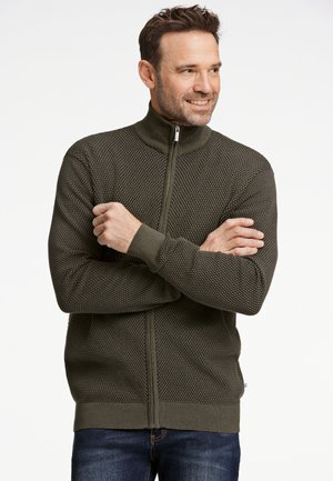 Pull zippé en tricot de couleur olivier foncé avec un motif texturé et des poignets côtelés. Il présente un col haut et deux poches latérales.