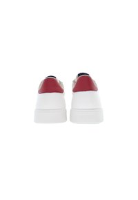 Witte sneakers met een gladde leren bovenkant, rode hielaccenten en gestructureerde beige details aan de zijkanten, met een platte witte zool.