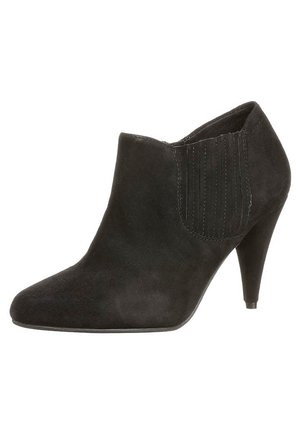 Musta mokkanahkainen nilkkurit, joissa on terävä kärki ja kovera korko. Varustettu joustavilla sivupaneeleilla, joissa pystysuoria uria helpottamaan jalkaan laittamista.