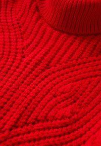 Pull en laine rouge avec un col haut à côtes et un motif texturé avec des lignes horizontales et diagonales. Fabriqué en fil épais.