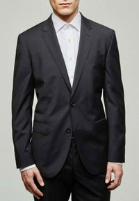 Veste de suit gris foncé avec un revers cranté, boutons à simple boutonnage, deux poches avant et une texture lisse, portée sur une chemise blanche.