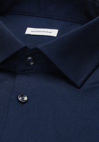 Granatowa teksturowana koszulka polo z dwoma guzikami i białą metką z napisem "seidensticker" wewnątrz kołnierza.