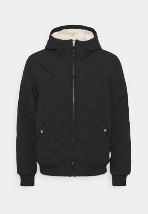 Schwarze gesteppte Jacke mit Frontreißverschluss, Kapuze mit weißem Fleece gefüttert, zwei Taschen mit Druckknopf und gerippten Bündchen und Saum.