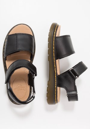 Zwarte leren sandalen met twee verstelbare banden en bruine zolen, weergegeven vanuit boven- en zijaanzicht op een witte achtergrond.