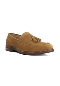 Suede loafers in tan, featuring a tassel accent, rounded toe, and stitched detailing. Brown leather sole with a slight heel.