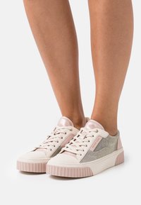 Sneakers basse in rosa pallido e argento. Presentano una tomaia in tessuto testurizzato, accenti rosa lucidi e una suola bianca zigrinata.