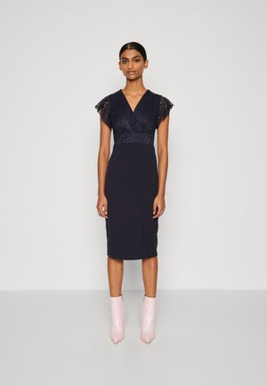 Navy blue dress with a lace bodice, short flutter sleeves, and a fitted pencil skirt. Paired with shiny pink ankle boots.