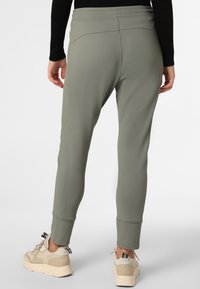 Gröna elastiska joggingbyxor med en figurnära design, med platta sömmar och avsmalnande ben. Bärs tillsammans med beigea chunky sneakers.