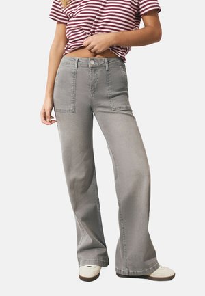 Jean large gris avec de grandes poches avant et une fermeture à bouton, fabriqué à partir d'un denim doux avec une texture lisse.