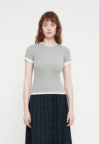 Grå kortermet T-skjorte med hvit krage og ermekanter, med en tettsittende design og en jevn tekstur, brukt med et rutete skjørt.