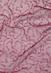 Przezroczysta różowa tkanina o teksturowanym wzorze z siateczki, zdobiona wirującymi liniami i małymi prostokątnymi koralikami w różnych odcieniach różu.