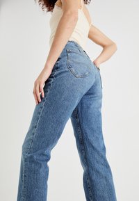 Hoge taille blauwe spijkerbroek van denim, met een relaxte pasvorm, rechte pijpen, achterzakken en minimale stikseldetails.