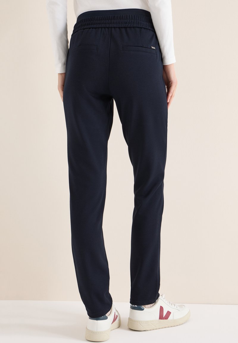 Námořnické tepláky s volným střihem, s elastickým pasem a dvěma zadními kapsami, vyrobené z měkké, texturované látky.