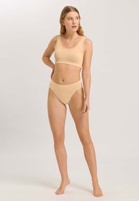 Conjunto de sujetador beige sin costuras y braguitas de cintura alta, con una textura suave, escote en forma de barco y un diseño minimalista sin adornos.