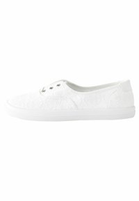 Sneaker bianco slip-on con un delicato motivo in pizzo floreale, tre fori per i lacci e suola piatta in gomma.