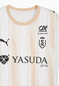 Maglietta sportiva bianca con design in legno chiaro, colletto rotondo, e loghi neri: Puma, CA Nord Est, gruppo Yasuda e SR.