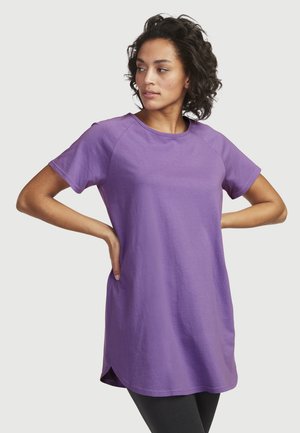 Paarse tuniek met korte mouwen en een ronde halslijn, voorzien van zijsplitsen. Gemaakt van zachte, gladde stof, met een relaxte pasvorm en raglanmouwen.