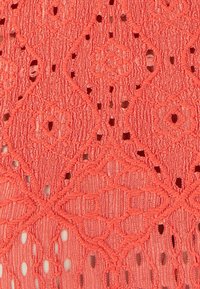 Tessuto di pizzo corallo con intricate fantasie floreali e geometriche, con fori distribuiti uniformemente e superficie testurizzata. Adatto per indumenti leggeri.