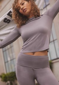 Hosszú ujjú, testhezálló felső, hozzáillő, magas derekú leggings világos levendula színű anyagból. Simaság, minimális varrások és rövidített fazon.
