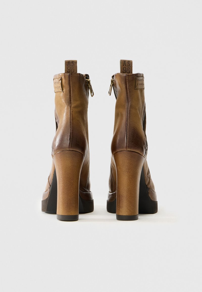 Bottines en cuir brun avec un talon block haut, fermeture éclair à l'arrière et couture apparente. Fini texturé et détail de logo sur le talon.
