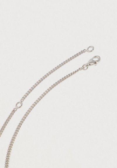 Stříbrný řetízek s karabinkou a malým kulatým očekem na světlém pozadí.