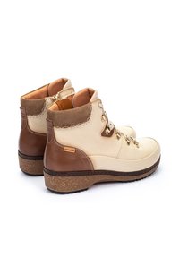Bottines à lacets marron et crème avec une tige en cuir texturé, des détails de couture subtils et une semelle rembourrée pour le confort.