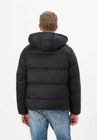 Sort pufferjakke med hætte, der har et quiltet design og synlige sømme. Materialet har en glat tekstur og fyld til isolering.