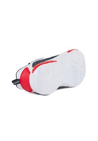Zapatilla con suela de goma blanca, parte superior negra y acento rojo en el talón. Cuenta con un agarre texturizado y una pestaña de tira para facilitar el calzado.