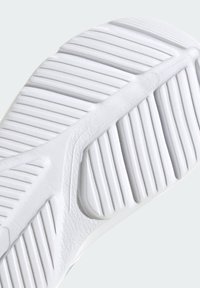 Suela de zapato de goma blanca con profundas ranuras y patrones estriados, textura suave con un ligero brillo, diseñada para ofrecer tracción y comodidad.