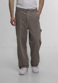 Brune cargo bukser med afslappet pasform, med sidelommer, knaplukning og et slidstærkt bomuldsstof. Sammen med hvide sneakers.