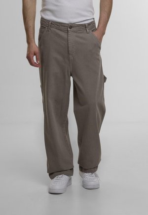 Brune cargo bukser med en afslappet pasform, der har sidelommer, knaplukning og et slidstærkt bomuldsstof. Sammen med hvide sneakers.