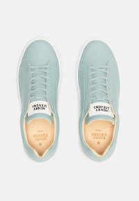 Sneakers in pelle azzurro chiaro con suole in gomma bianca, dotati di chiusura con lacci e etichetta del marchio sulla linguetta. Texture liscia e design minimalista.