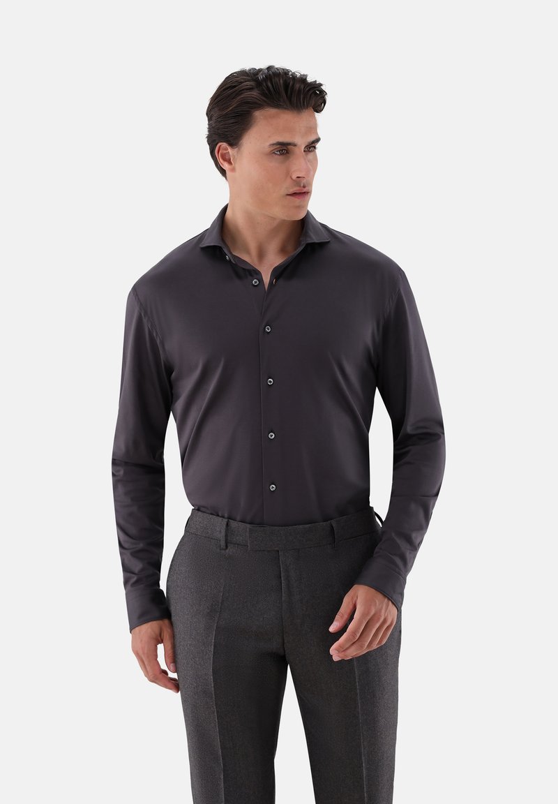 Camicia a maniche lunghe grigio scuro con una texture liscia, bottone frontale, colletto classico e bottoni neri, abbinata a pantaloni grigi con motivo.