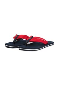 Tongs pour hommes avec des brides tissées rouges et des semelles bleu marine. Caractéristiques d'accents rayés blancs et logo "TOMMY HILFIGER" sur la bride.